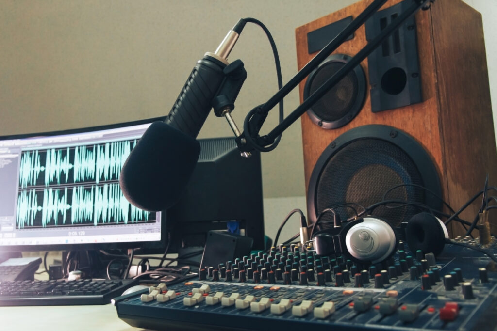 Radio host microphone, mixing console, sound column and headphones on the background of a computer monitor. Radio Studio